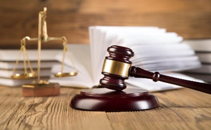 Immobilienrecht Richterhammer und Justizwaage vor aufgeschlagenem Gesetzbuch als Symbol für Immobilienrecht